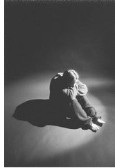 Bild einer traurigen Person in dunklem, leeren Raum